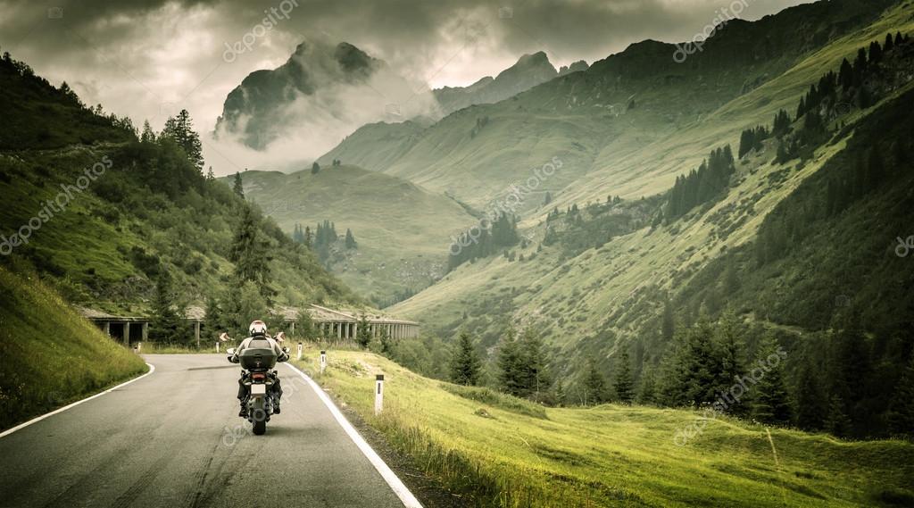 Motociclisti con antipioggia che ridono sotto un cielo nuvoloso