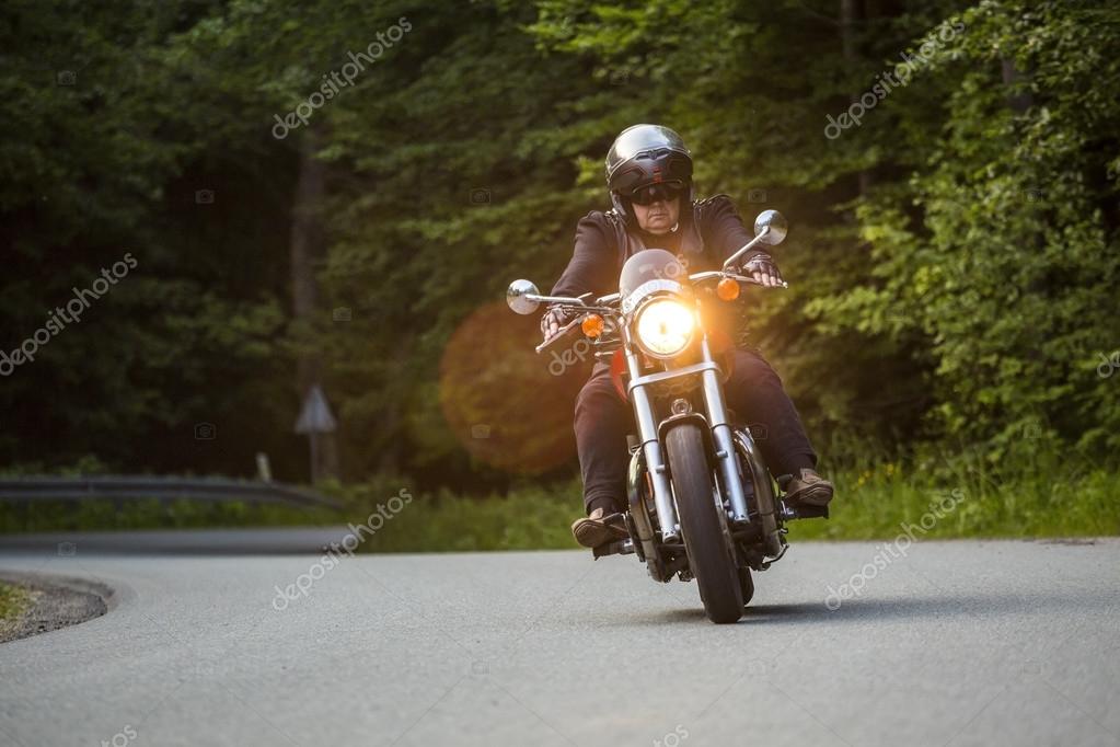 Strada nel bosco illuminata da raggi di sole con una moto in movimento